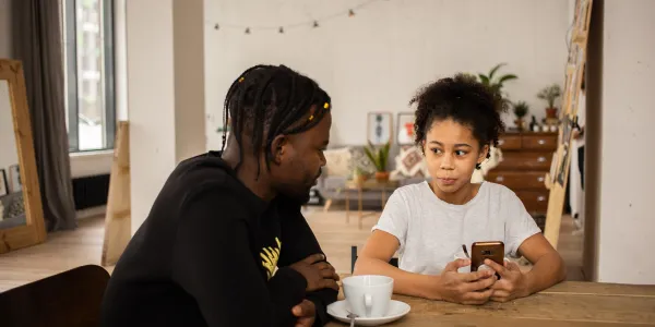 Dad and son looking at a phone together at the kitchen table