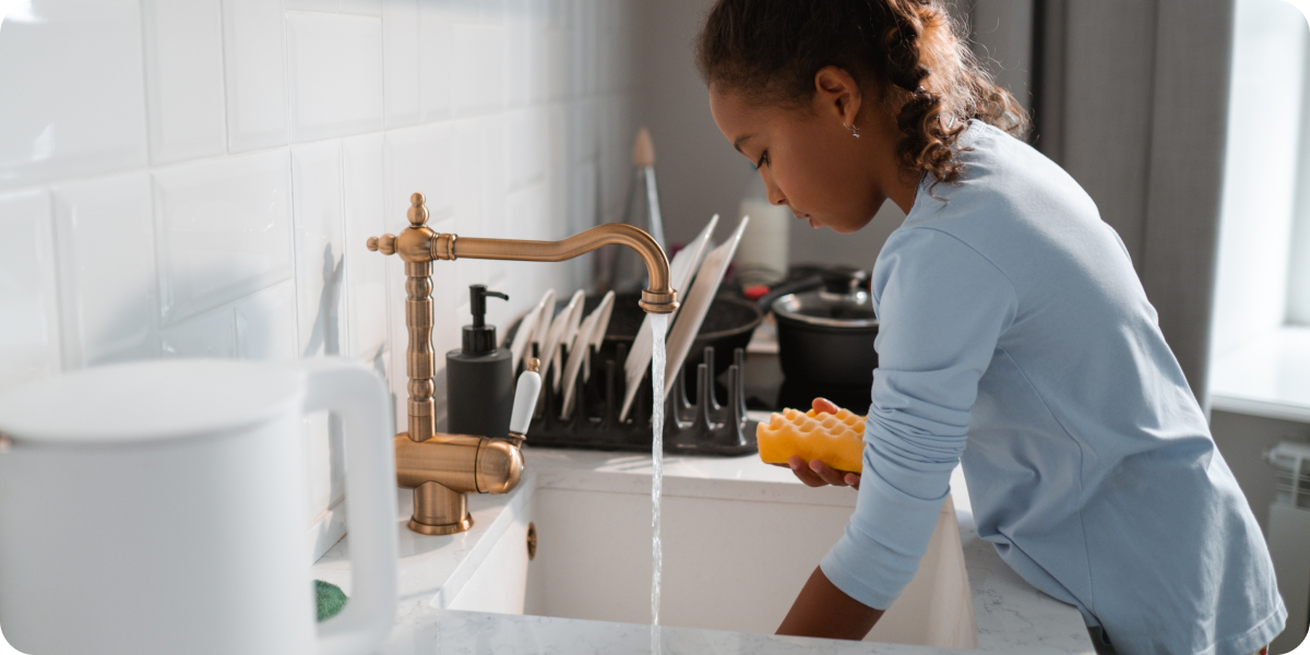Girl washing dishes at the kitchen sink