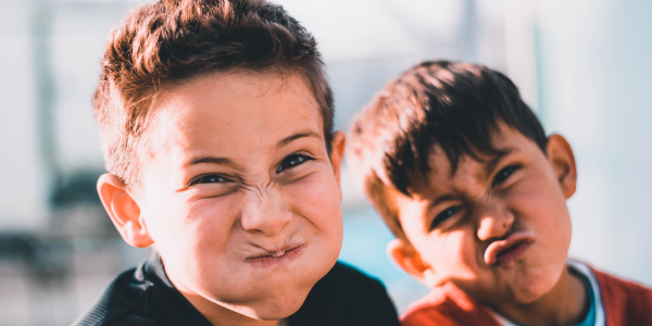 Two smiling boys posing together outdoors