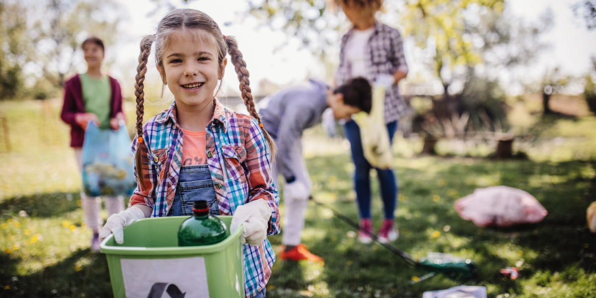 Girl holding a recycling bin with family doing yard work in the background