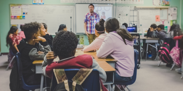 Teacher and students in a classroom with hands raised